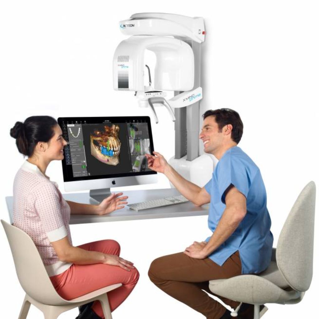 A dentist and patient sitting down and looking at a monitor that shows an x-ray taken by the Acteon X Mind Prime dental scanner